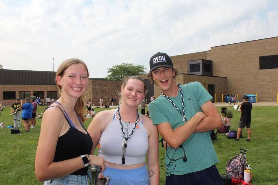 Image 1 of 2 Three students standing outside in summer clothes smiling for a picture